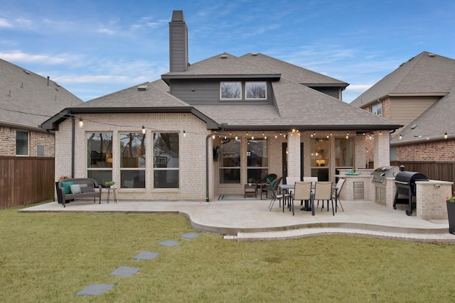 rear view of house featuring exterior kitchen, a yard, brick siding, and fence