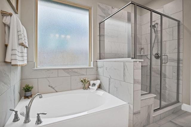 bathroom featuring marble finish floor, a garden tub, and a shower stall