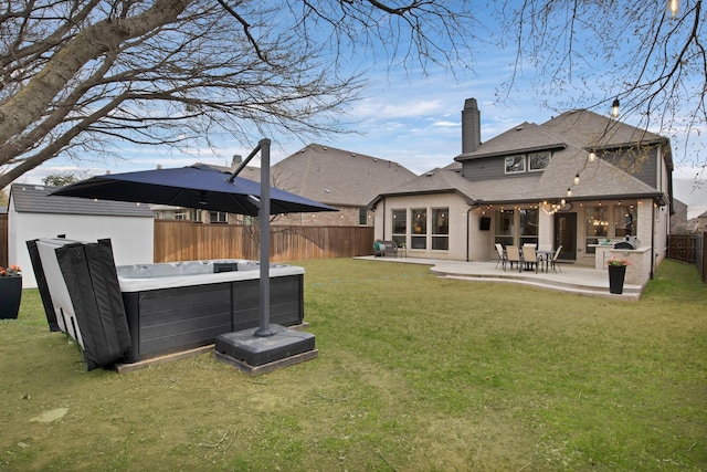 back of house featuring a patio, a fenced backyard, brick siding, a lawn, and a hot tub