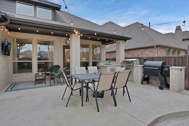 view of patio / terrace with exterior kitchen, outdoor dining space, a grill, and fence