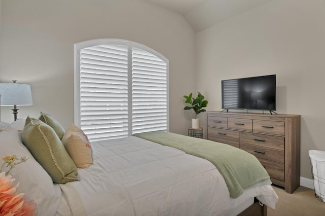 bedroom featuring light carpet and vaulted ceiling