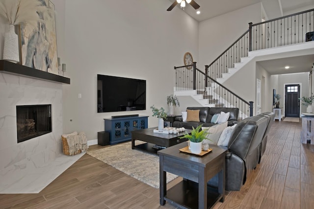 living area with a towering ceiling, stairway, wood finished floors, and a tile fireplace