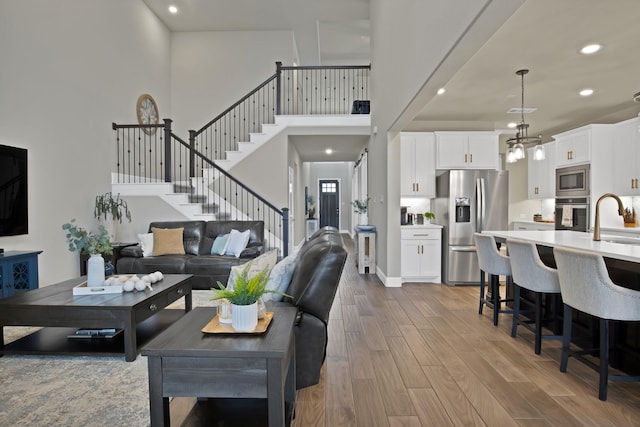 living area featuring stairway, wood finished floors, a towering ceiling, and recessed lighting