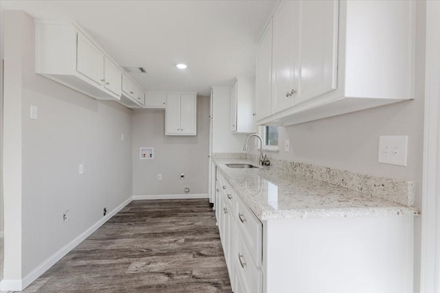 kitchen featuring baseboards, white cabinets, dark wood-style floors, light stone countertops, and a sink