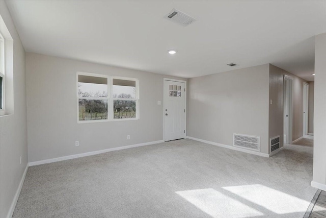 empty room with carpet, visible vents, and baseboards