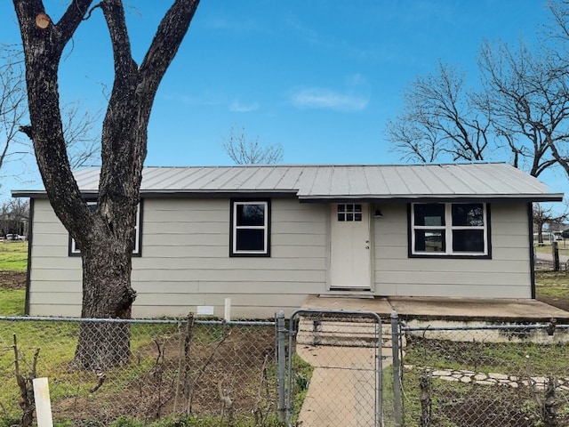 view of front of house featuring a standing seam roof, a fenced front yard, a gate, and metal roof