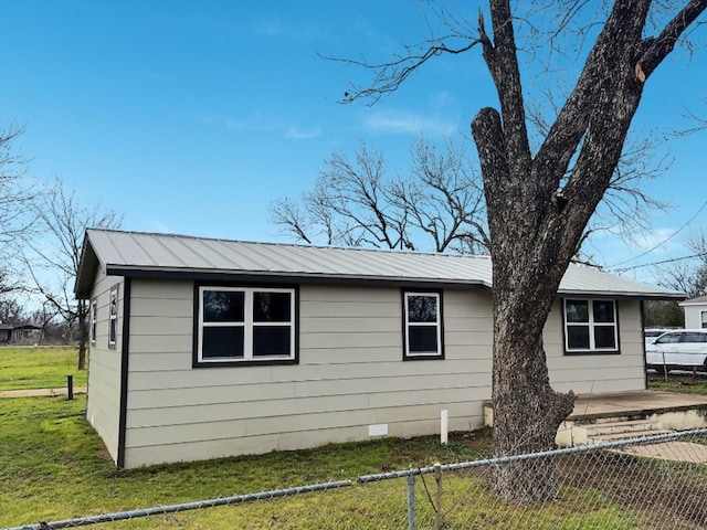 view of side of home with crawl space, fence private yard, metal roof, and a yard