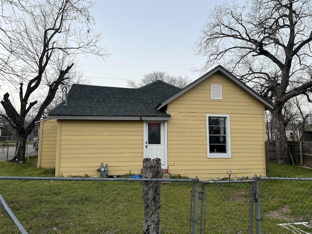 bungalow-style house featuring fence private yard, a shingled roof, and a front lawn