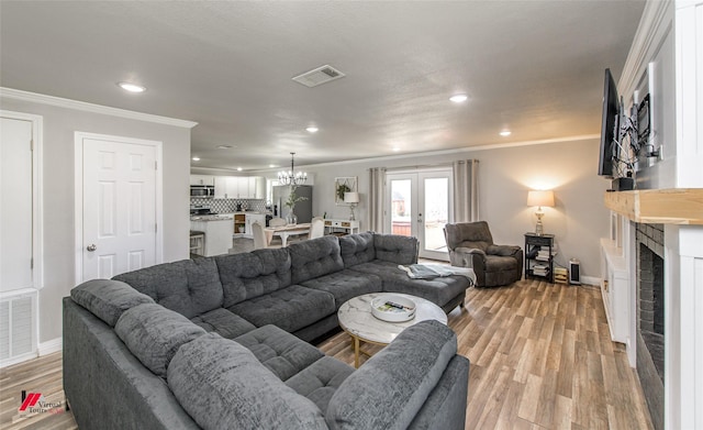 living area with light wood finished floors, visible vents, and crown molding