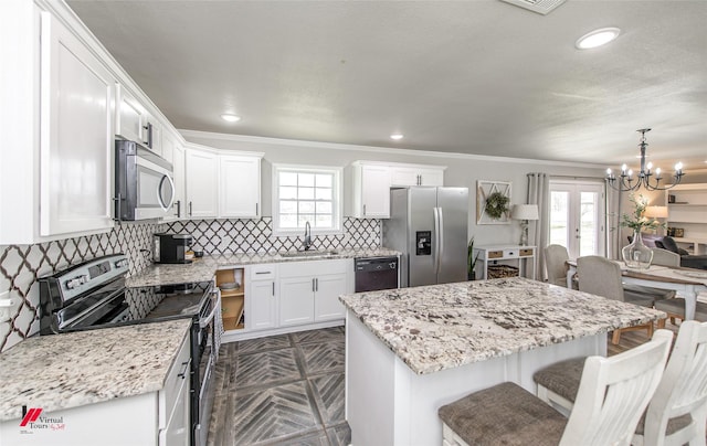 kitchen featuring appliances with stainless steel finishes, a breakfast bar, white cabinetry, and a sink