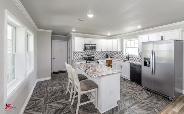 kitchen featuring visible vents, white cabinets, a center island, stainless steel appliances, and backsplash