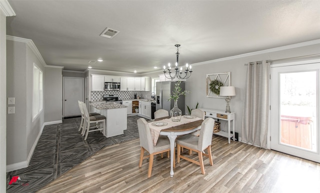 dining space with wood finished floors, visible vents, and crown molding