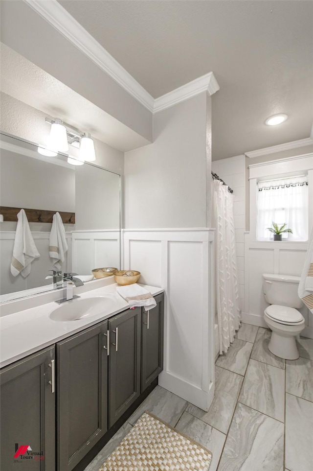 full bathroom featuring toilet, a wainscoted wall, marble finish floor, crown molding, and vanity