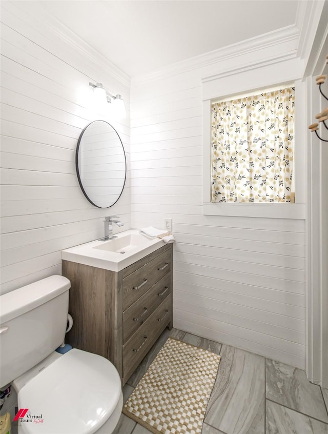 bathroom with toilet, marble finish floor, ornamental molding, and vanity