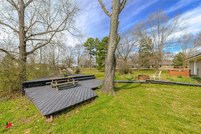 view of community featuring a yard, a wooden deck, and a jacuzzi