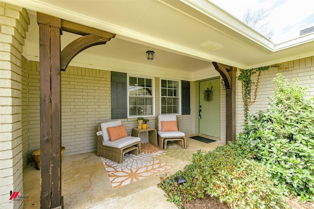 doorway to property featuring a porch and brick siding