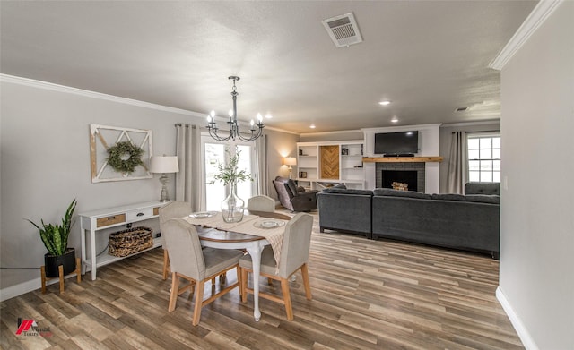 dining space with crown molding, visible vents, a brick fireplace, wood finished floors, and baseboards