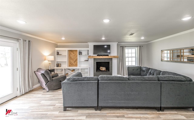 living area featuring ornamental molding, light wood-type flooring, visible vents, and a brick fireplace