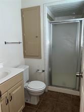 full bathroom featuring a shower stall, vanity, and toilet