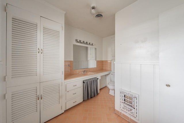 bathroom with heating unit, visible vents, toilet, wainscoting, and tile patterned flooring