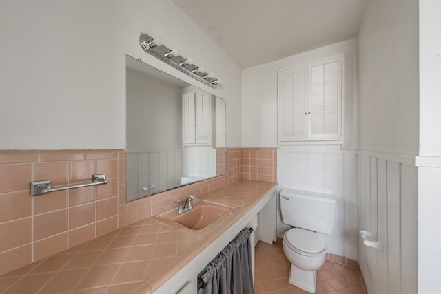 bathroom featuring toilet, a wainscoted wall, vanity, and tile patterned floors