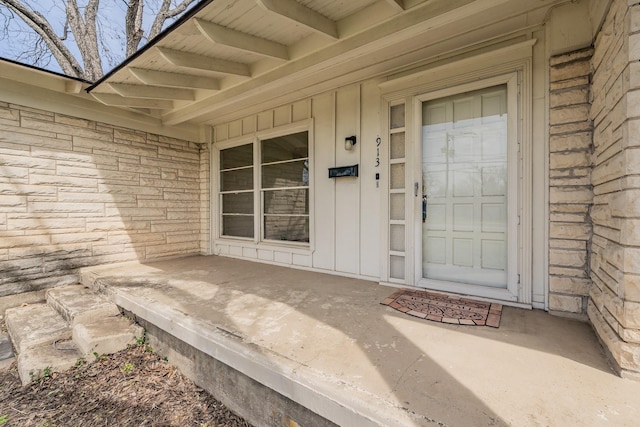 entrance to property featuring covered porch and brick siding