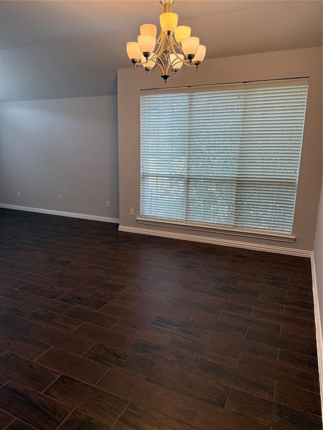 spare room featuring baseboards, wood finish floors, vaulted ceiling, and an inviting chandelier