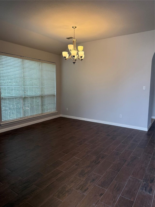 spare room featuring an inviting chandelier, visible vents, baseboards, and dark wood-style flooring