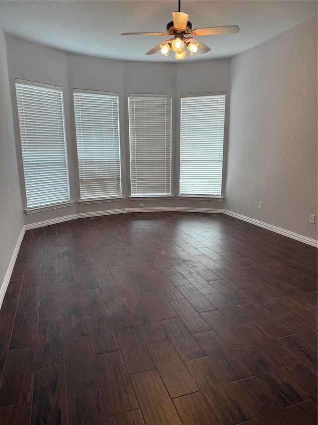 spare room with dark wood-type flooring, baseboards, and a ceiling fan