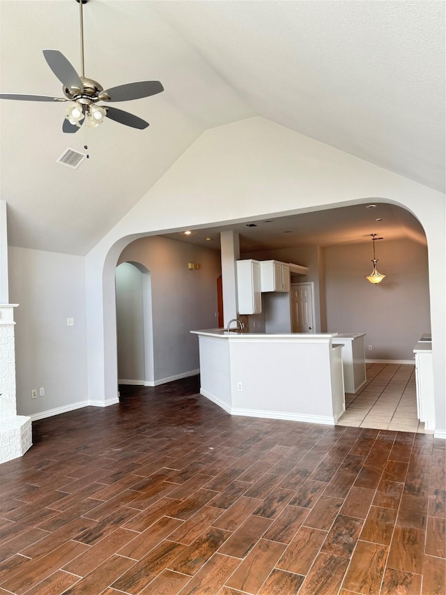 kitchen featuring arched walkways, visible vents, white cabinetry, open floor plan, and dark wood finished floors