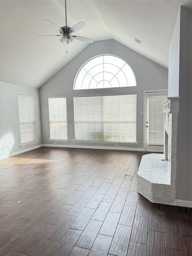 unfurnished living room with wood finish floors, visible vents, a ceiling fan, a brick fireplace, and baseboards