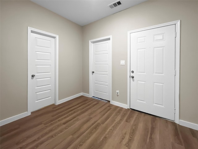 foyer featuring dark wood-style floors, baseboards, and visible vents