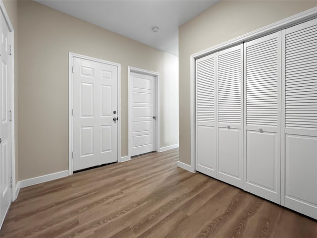 unfurnished bedroom featuring baseboards, a closet, and wood finished floors