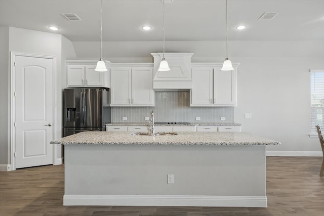 4303 Juniper Ln, Melissa, TX 75454 - kitchen with visible vents, an island with sink, backsplash, stainless steel fridge, and white cabinets
