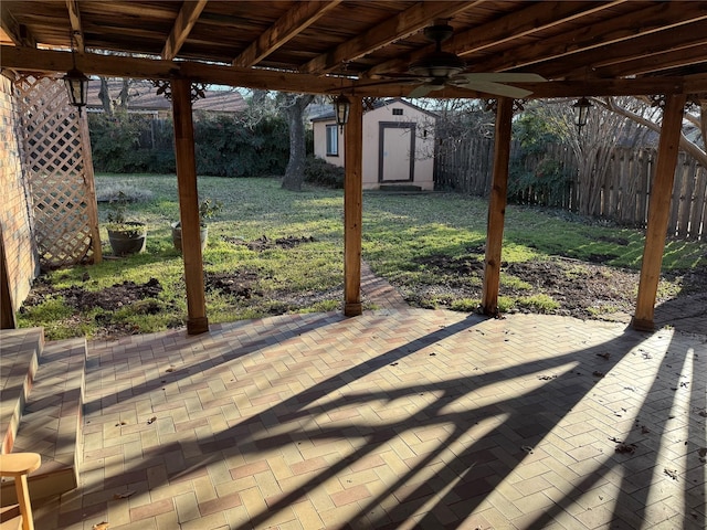 view of patio / terrace with an outbuilding, fence, and a shed