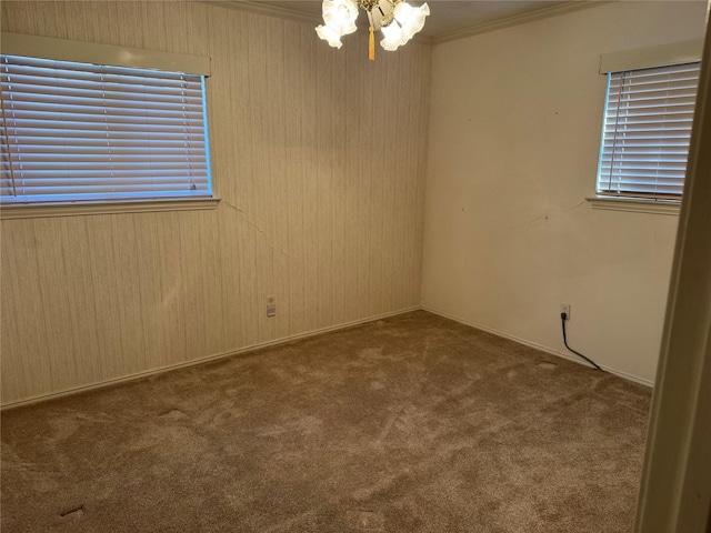 spare room with ornamental molding, carpet flooring, and a notable chandelier