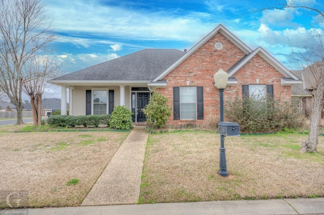 view of front of home featuring a shingled roof, a front lawn, and brick siding