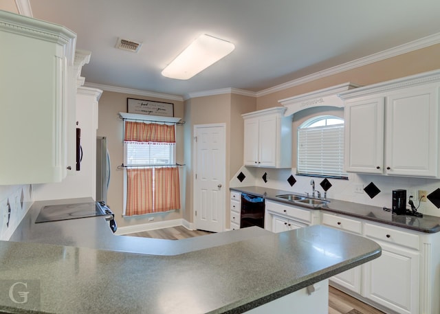 kitchen with visible vents, white cabinets, dark countertops, ornamental molding, and a sink