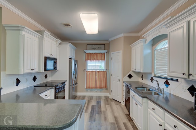 kitchen with dark countertops, light wood-style flooring, crown molding, black appliances, and a sink