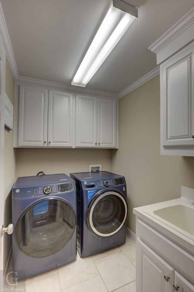 clothes washing area featuring cabinet space, light tile patterned floors, washer and clothes dryer, crown molding, and a sink