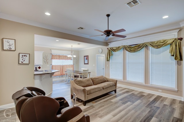 living room featuring light wood-type flooring, baseboards, visible vents, and crown molding