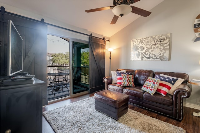 living area with lofted ceiling, a barn door, a ceiling fan, wood finished floors, and baseboards