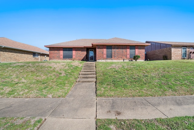 view of front of home featuring roof with shingles, a front lawn, and brick siding