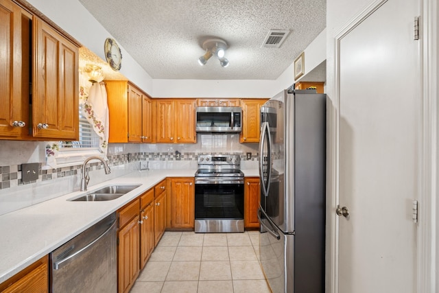 kitchen with light tile patterned floors, stainless steel appliances, a sink, light countertops, and backsplash