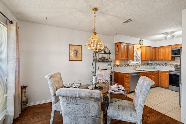 dining room featuring a textured ceiling, visible vents, and light wood-style floors