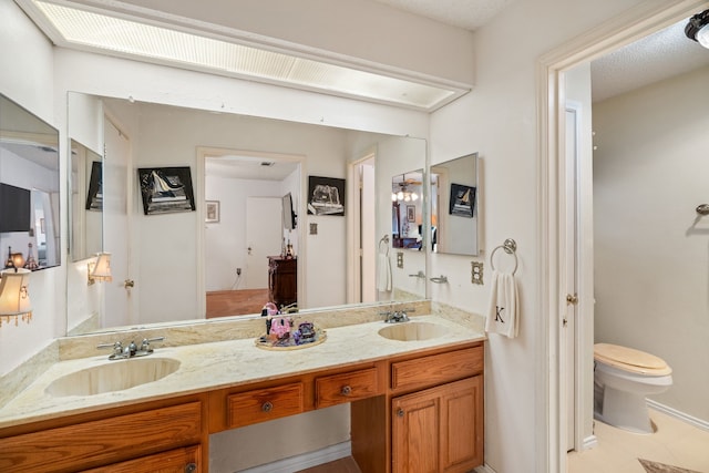 bathroom with a sink, toilet, and double vanity