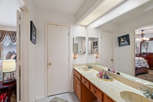 bathroom featuring a textured ceiling, double vanity, ensuite bath, and a sink