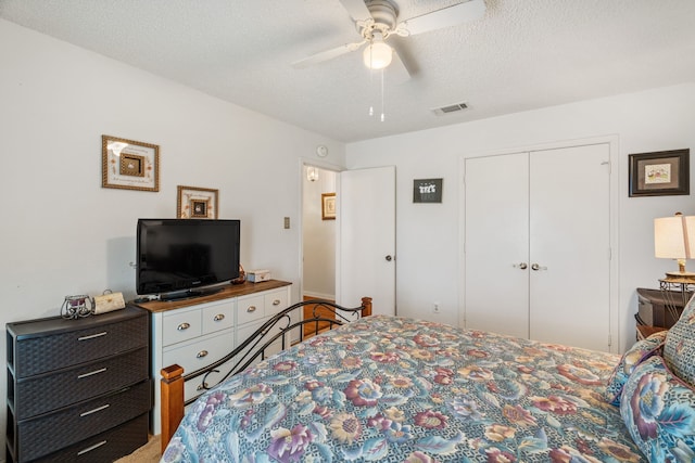 bedroom with a closet, visible vents, a ceiling fan, carpet flooring, and a textured ceiling