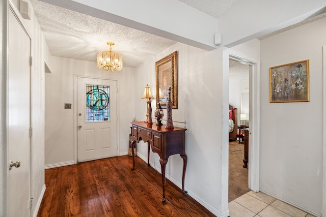 entryway with an inviting chandelier, baseboards, visible vents, and a textured ceiling