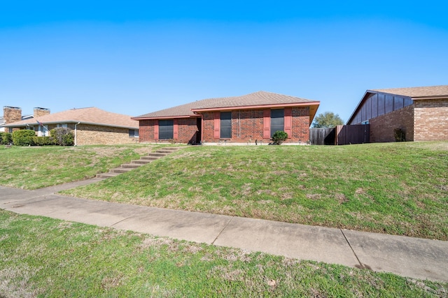 view of front of house featuring fence, a front lawn, and brick siding